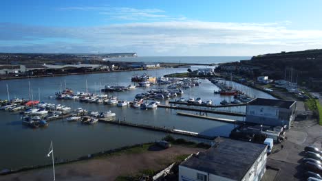 wide angle establishing aerial shot small marina with boats moored to dock