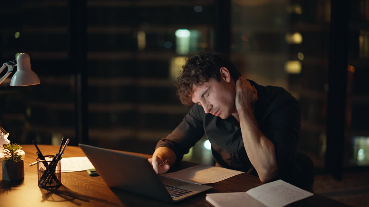Depressed worker looking laptop at night company workspace closeup. Tired man