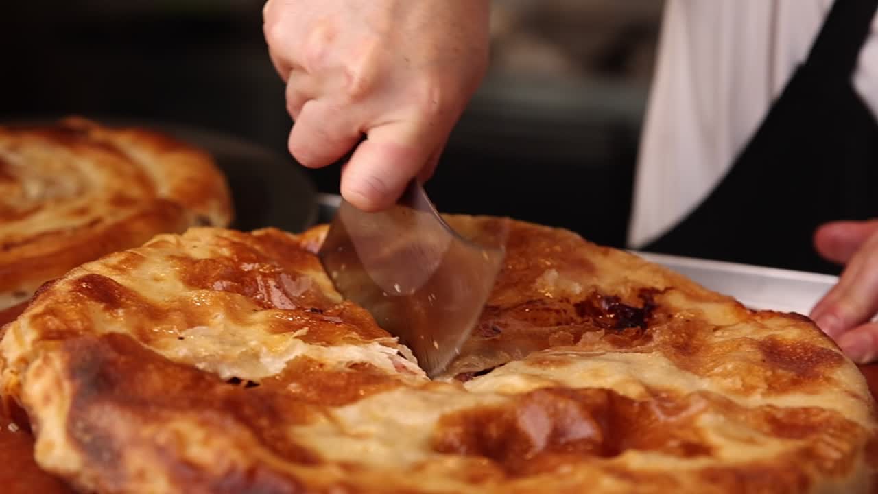 Primo piano di una mano che taglia una pasta salata dorata con un coltello