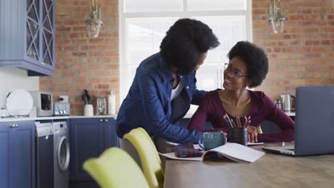 madre y hija afroamericanas felices haciendo la tarea juntos en la cocina