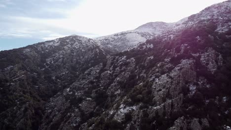 Epic-aerial-of-mountain-range-snowcapped,-rising-towards-peak,-Sardinia
