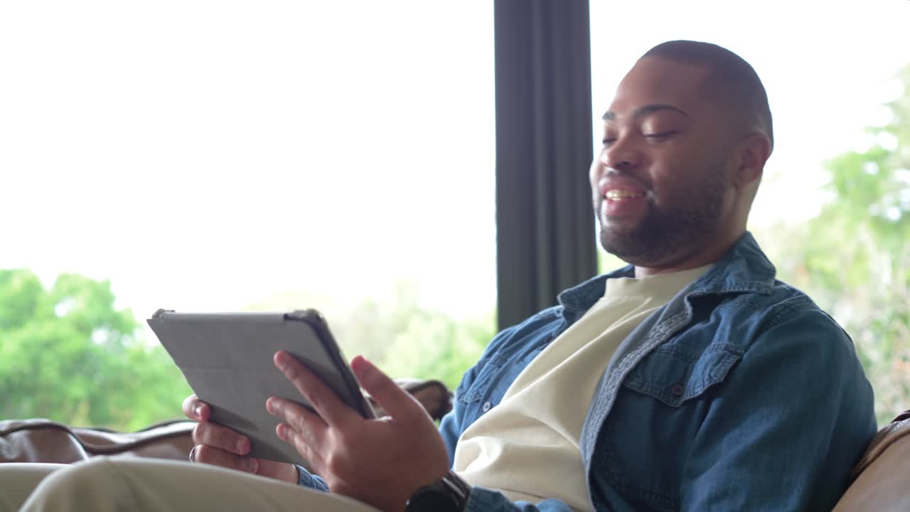 Man receiving update on tablet frowning then smiling raising fist celebrating then glancing outside