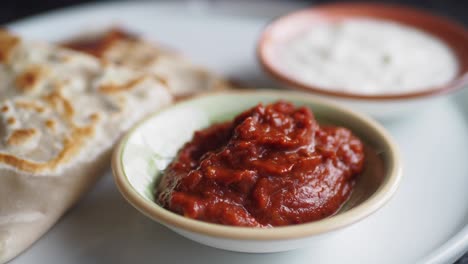 close-up of red sauce with flatbread and white sauce