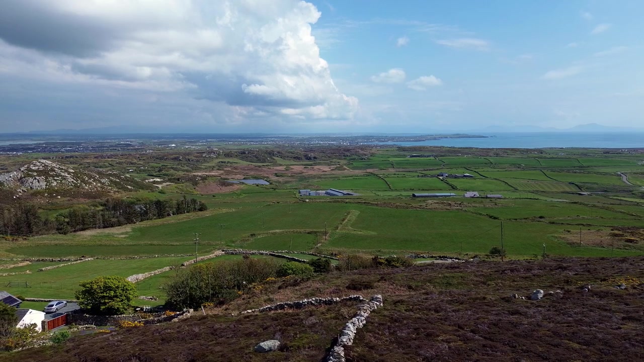 Ampia vista panoramica aerea attraverso un fertile paesaggio agricolo insulare gallese e un paesaggio marino nel Galles del nord.