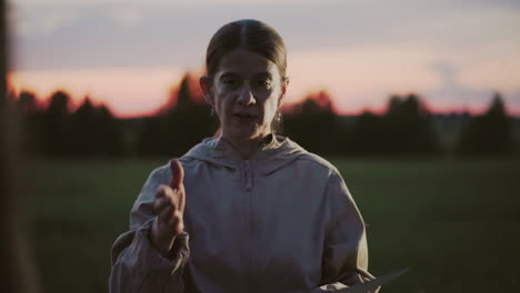 close up of instructor extending hand to shake participant hand during outdoor lesson in tall grass field under warm sunset sky with blurred trees background