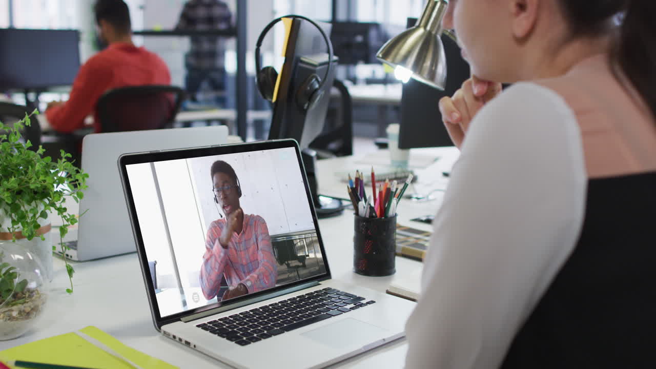 Caucasian businesswoman sitting at desk using laptop having video call with male colleague