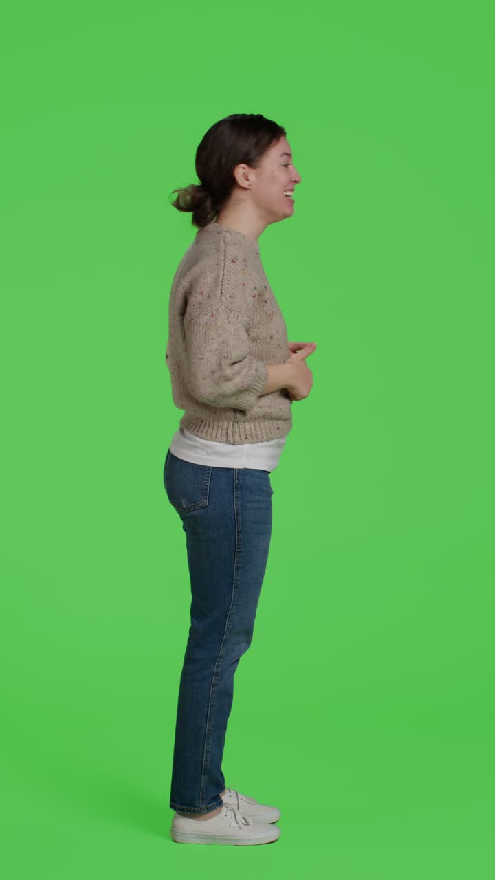 Video verticale: profilo di una donna felice che fa il simbolo del pollice in su su uno schermo verde in studio