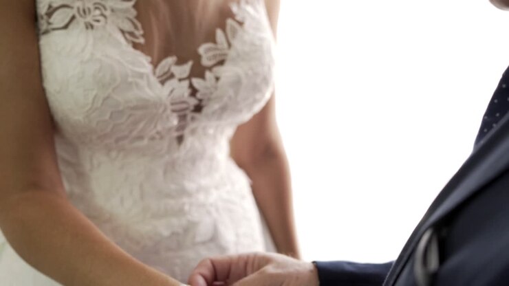 Bridesmaid helps bride putting on a wrist bracelet on wedding day
