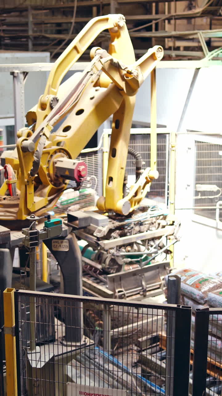 Automated plant indoors. Robotic construction puts the bags on a support on industrial factory background. Vertical video