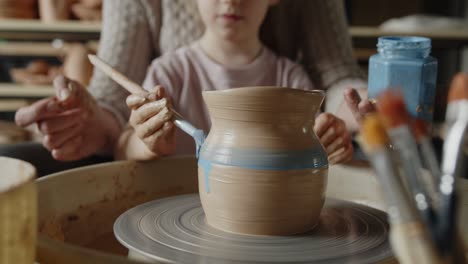 grandmother teaches her granddaughter working on a pottery rotating wheel