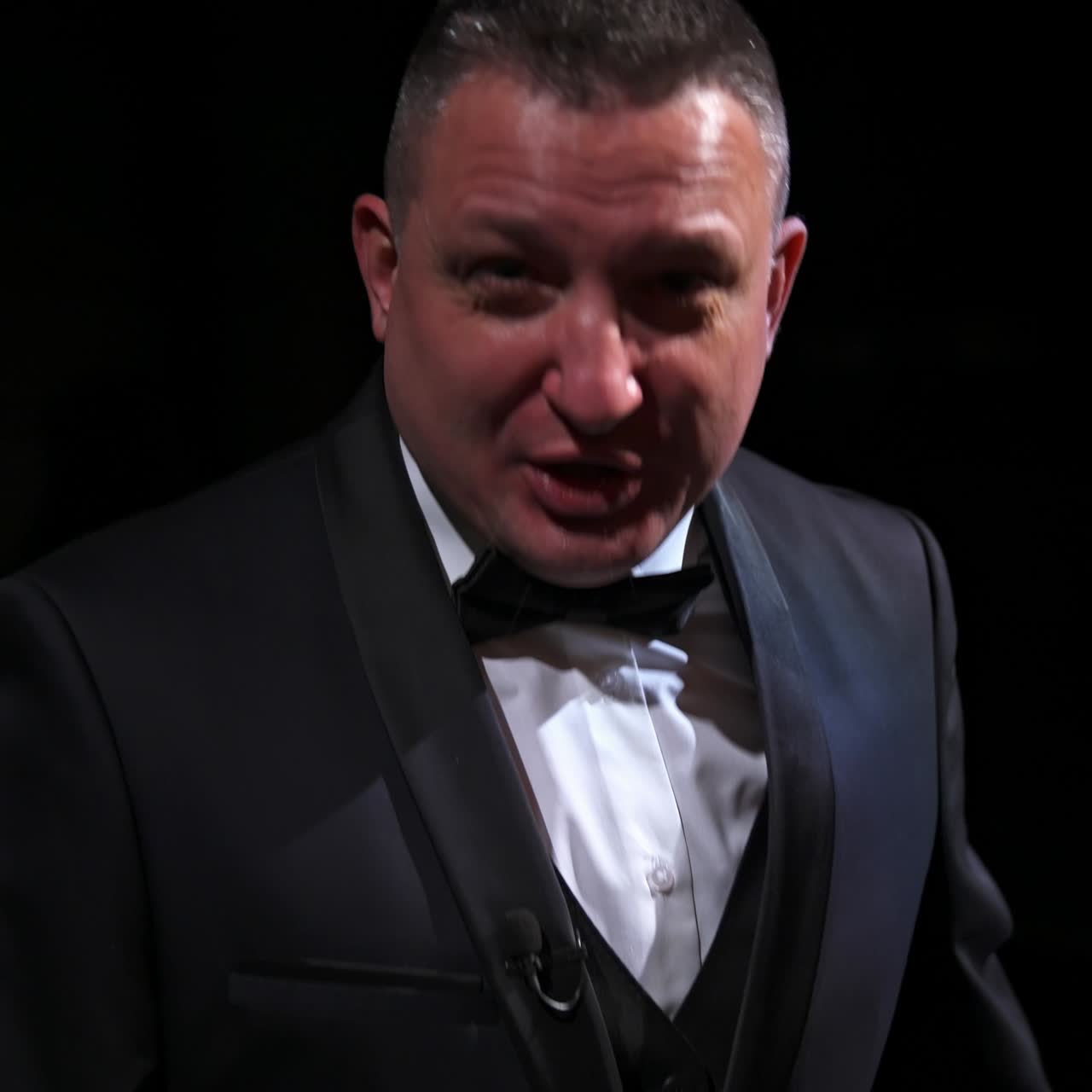Portrait of a comedian talking. Cheerful actor in suit telling funny stories and gesticulating a lot. Man performing on stage