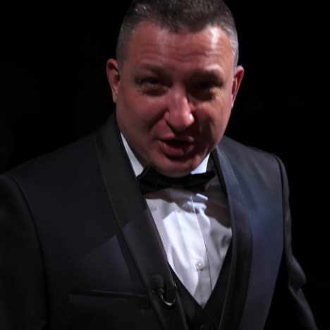 portrait of a comedian talking. cheerful actor in suit telling funny stories and gesticulating a lot. man performing on stage