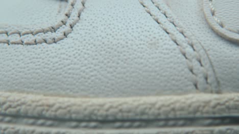 A-macro-close-up-shot-of-a-white-sneaker-sole,-miniature-shoe-display-on-a-360-rotating-stand-with-reflection,-holes-and-stitches,-sport-wear-design,-professional-lighting,-cinematic-4K-video