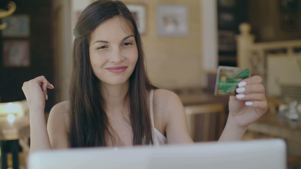 Woman shopping online at cafe using credit card