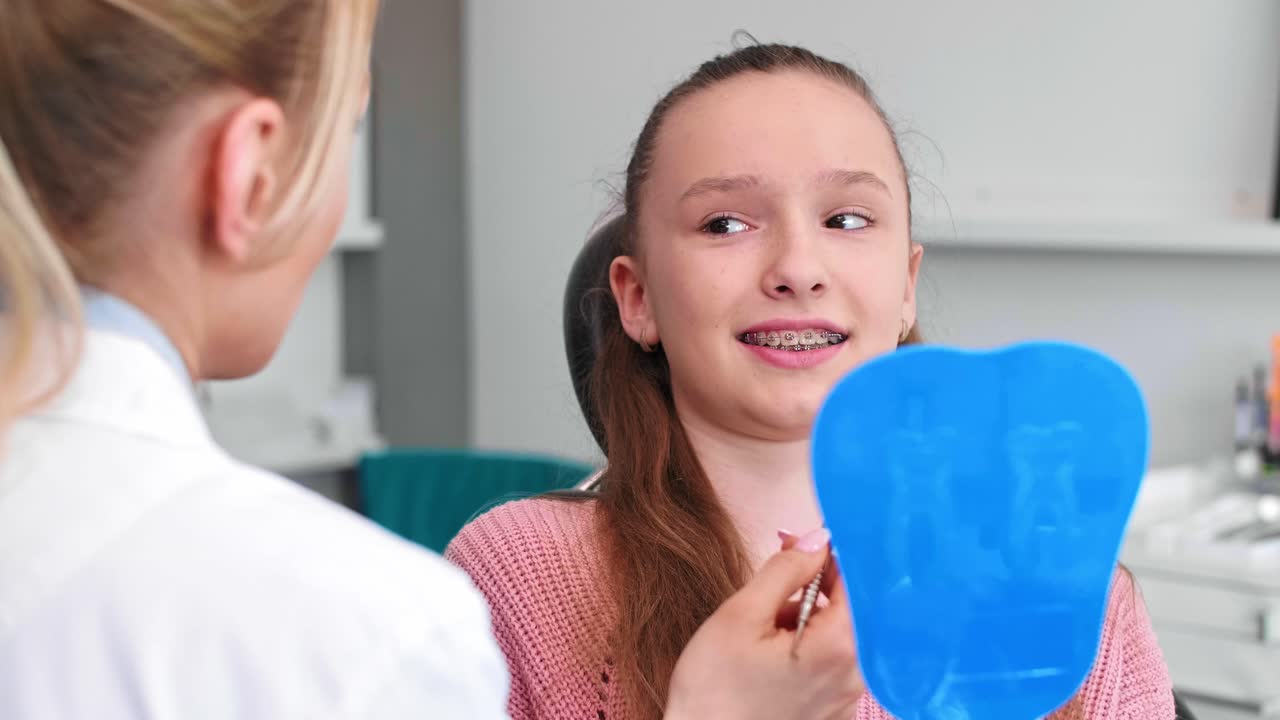 Female orthodontist examining child's teeth in dentist's office