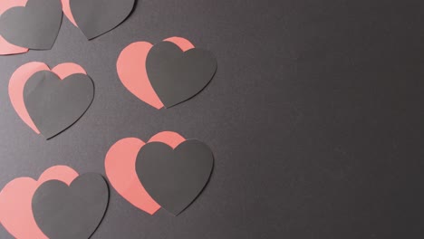 Video-of-red-and-black-paper-heart-shapes-on-black-background-with-copy-space