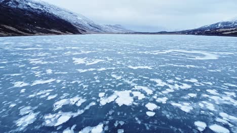 Snowy-mountains-near-glacier-in-volcanic-terrain-against-overcast-sky