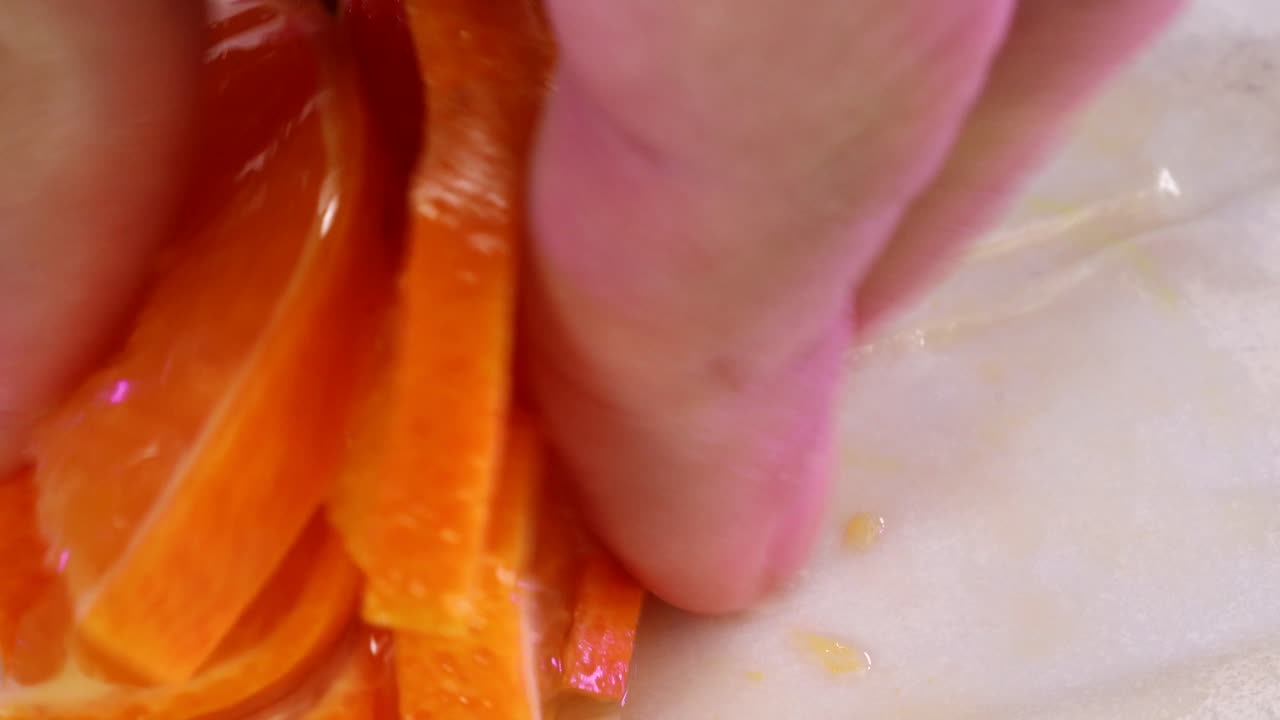 흰 종이 표면에 신선한 오렌지 조각을 손으로 쥐어 짜다