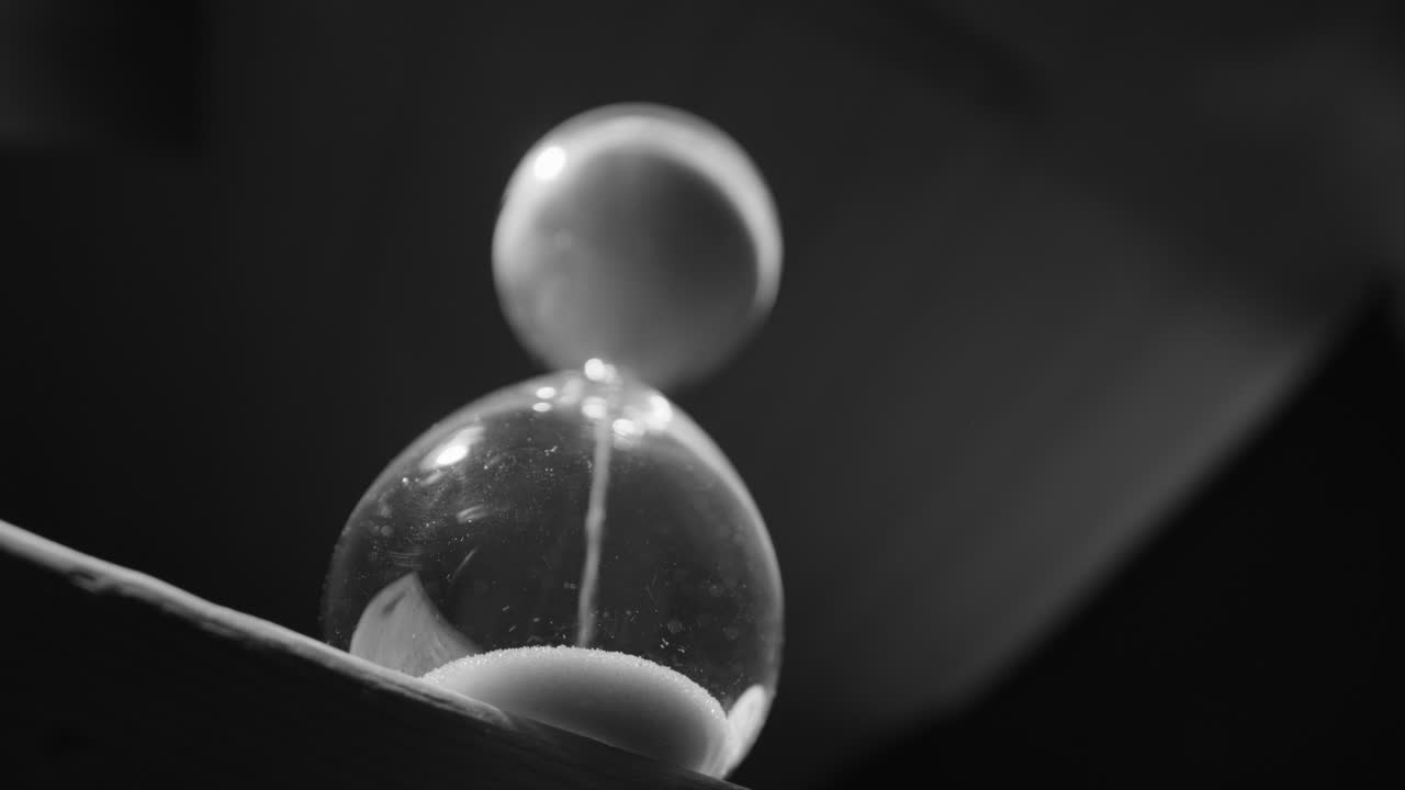 reloj de arena con granos de arena que caen, vista hacia arriba en blanco y negro