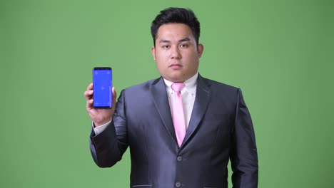 초록색 배경에 젊은 잘생긴 과체중 아시아 사업가