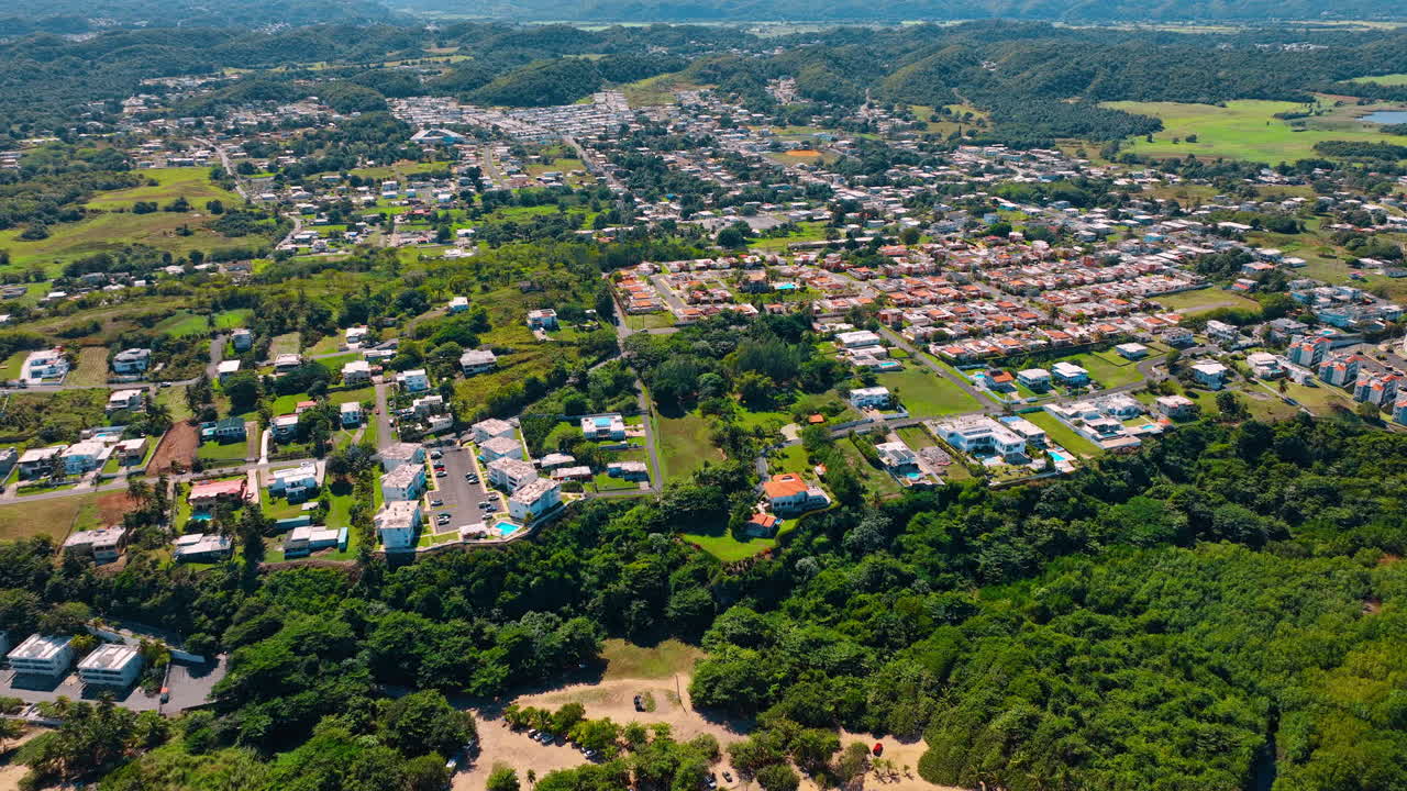 Avvicinamento a una spiaggia sabbiosa circondata da rigogliosa vegetazione. Filmato drone sul pittoresco paesaggio urbano di Porto Rico.