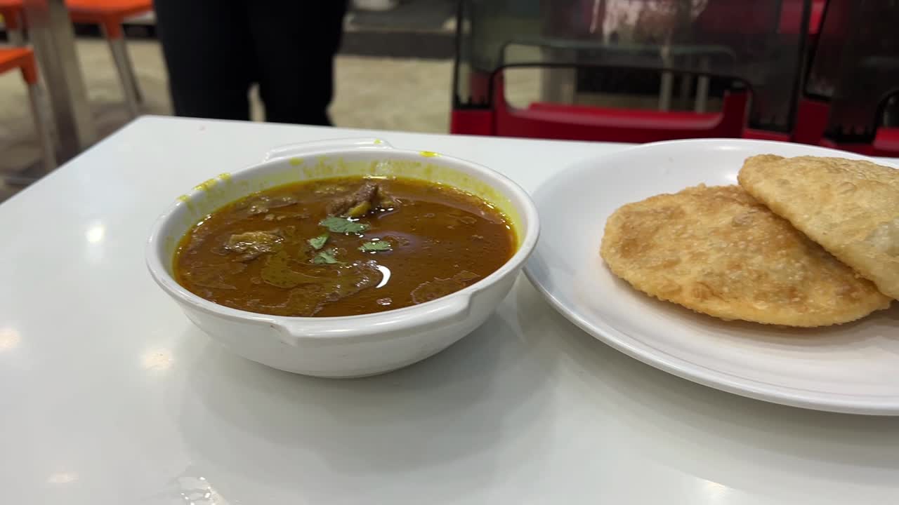 Close up shot of woman going to eat dal puri and mutton nihari.