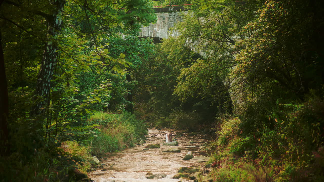 una mujer se salpica con agua cristalina de un río en las montañas