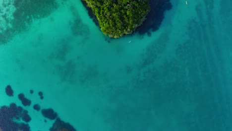 Toma-Cinematográfica-De-Una-Laguna-Azul-Que-Revela-Una-Pequeña-Formación-Rocosa-Isleña-Cerca-De-La-Playa-En-Una-Zona-Tropical-Durante-El-Día