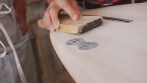 two caucasian male surfboard makers working in their studio and making a wooden surfboard together