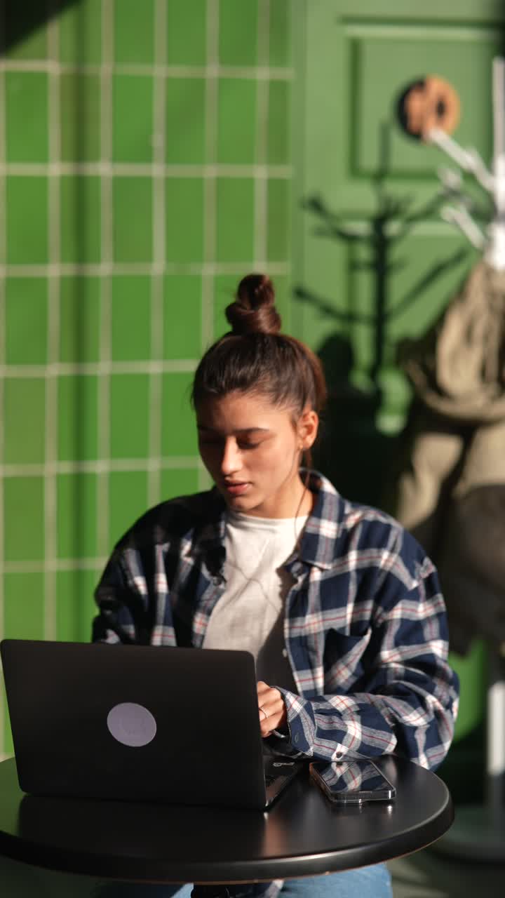 mujer joven trabajando en una computadora portátil en un café