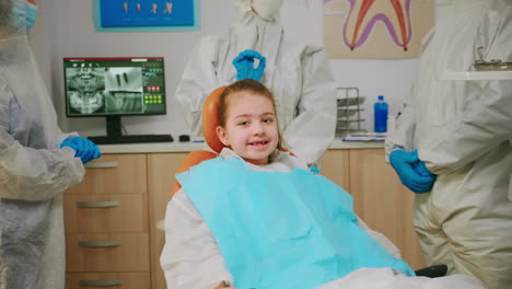 un primer plano de una chica feliz riendo ante la cámara visitando a un dentista durante una pandemia global.