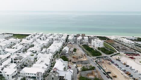 Vista-En-Movimiento-Giratorio-De-Las-Casas-Blancas-De-La-Playa-De-Alys,-Al-Fondo-Del-Lado-Del-Océano,-Algunas-Casas-En-Construcción-Y-Automóviles-En-El-Estacionamiento-Del-Lado-Derecho,