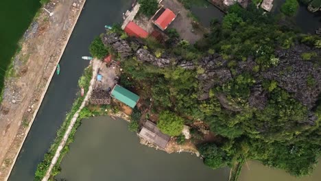 a descending aerial shot of property on a canal in tam coc, south east asia, reveals a group of small boats