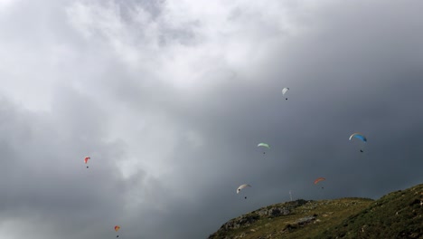 Gruppe-Von-Gleitschirmfliegern,-Die-An-Einem-Sehr-Bewölkten-Tag-Den-Berg-Hinuntergleiten