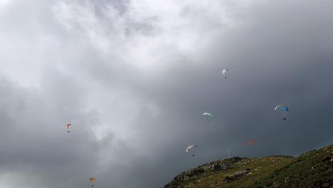 grupo de parapentes deslizándose por la montaña en un día muy nublado