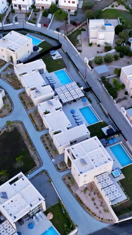 vertical drone shot tilting away from a hilltop, holiday village, dusk in greece