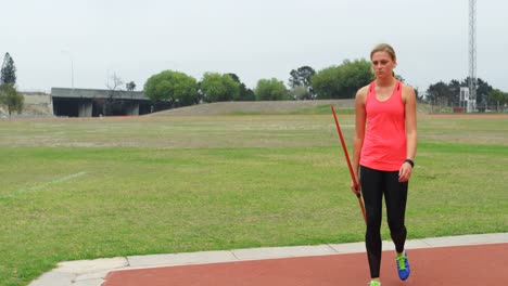 front view of caucasian female athlete walking with javelin throw at sports venue 4k