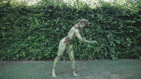 wide shot of a female model wearing green bodypaint dancing slowly in nature, in the style of nature-inspired forms