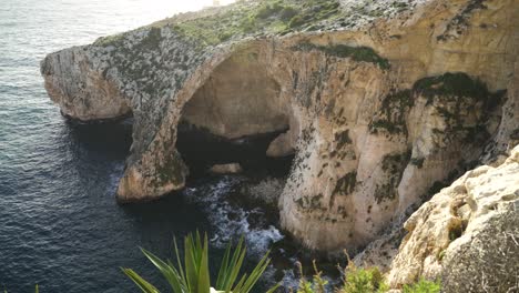 panoramic view of blue grotto sea caves being washed with waves of mediterranean sea