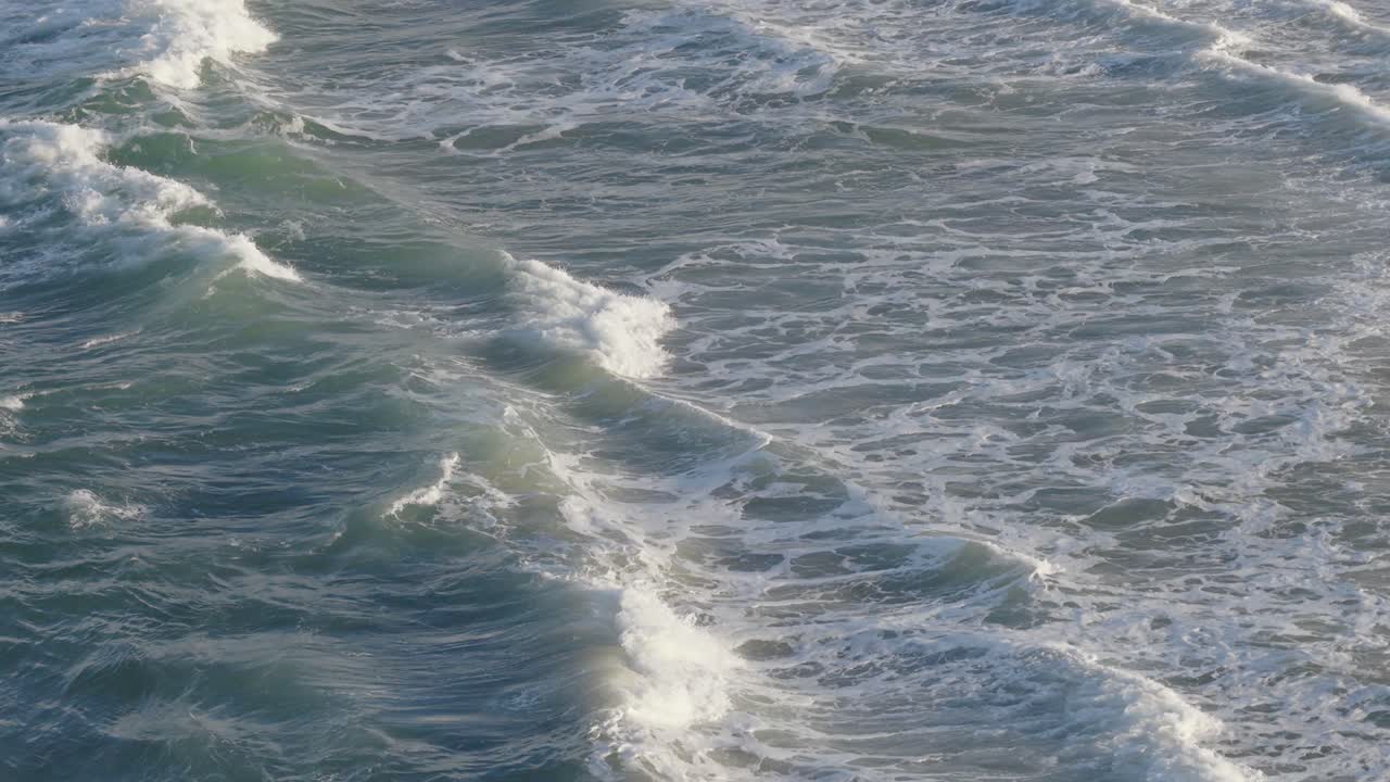 Drone captures rhythmic ocean waves along Gold Coast. Soft lighting highlights the dynamic movement and texture of the sea