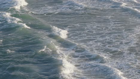 drone captures rhythmic ocean waves along gold coast. soft lighting highlights the dynamic movement and texture of the sea