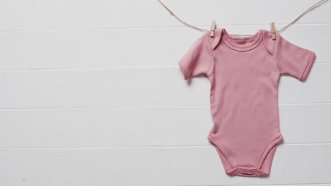 video of pink baby grow hanging on clothes begs on line with copy space on white background