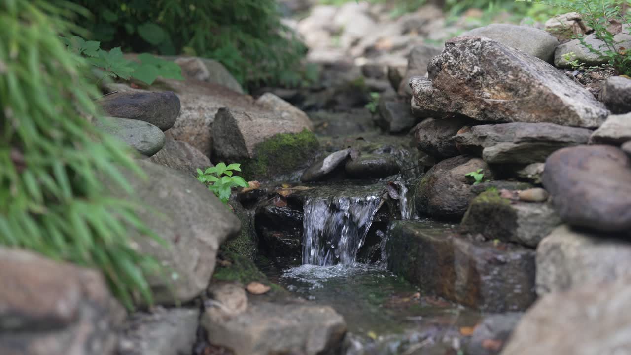 crystal-clear mountain stream flowing gently through a picturesque natural setting, featuring a charming little waterfall that adds to the beauty of the landscape