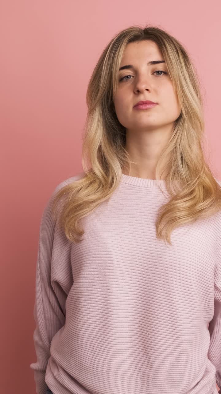Serious young woman thinking in pink studio