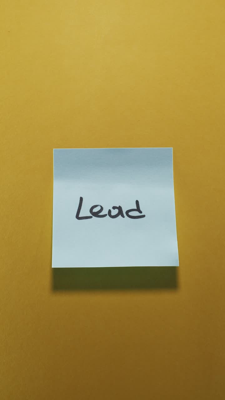 Lead written on light blue sticky note against a yellow background, symbolizing leadership and guidance