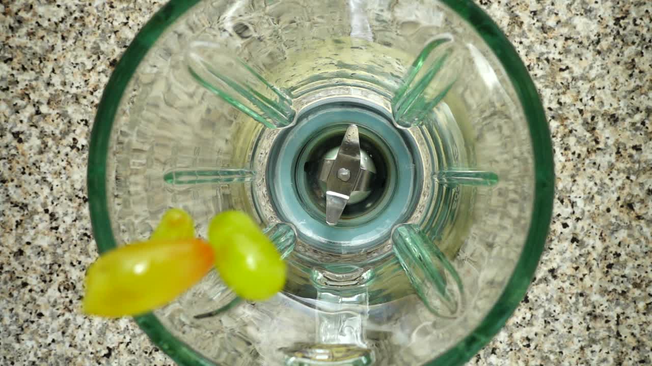 Grapes fall in a blender bowl. Slow motion. Shooting in kitchen. Top view