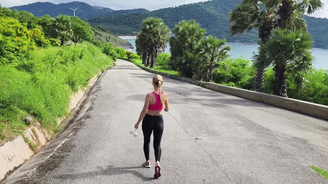 mujer caminando por una carretera panorámica con vistas a la costa