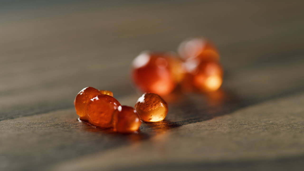 Nahaufnahme von glänzendem Lachsrogen auf dunkler Oberfläche