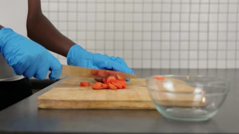 african lady cutting carrots with gloves - food prep during covid