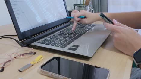 hands using a tablet for planning or organizing tasks, with a laptop nearby
